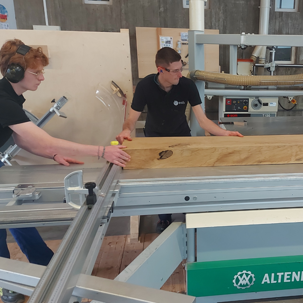 Deux élèves sont dans l'atelier, ils travaillent avec le bois. 